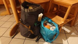Mein mit Einkäufen gefüllter grauer Rucksack und eine ebenso gefüllte türkise Stofftasche stehen in unserer Küche