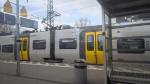 Foto aus einem Zugfenster heraus auf einen Bahnsteig, mit einer Regionalbahn auf dem Gleis